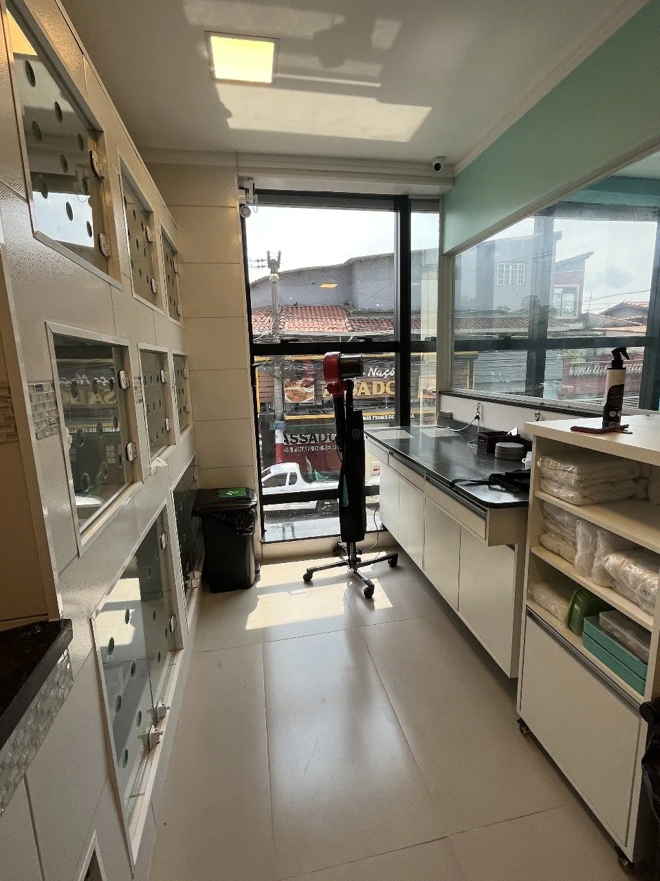 Sala interna da clínica, com bancada de atendimento e baias de vidro